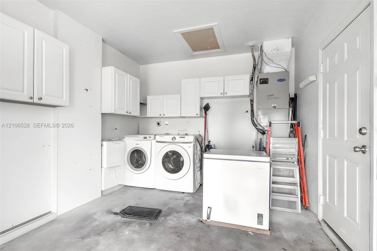 2615 NW 14th Street, Fort Lauderdale, FL 33311 Utility area featuring wall-mounted white cabinetry, an HVAC system, and a six-panel entry door