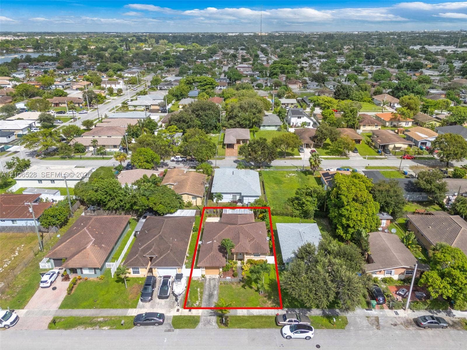 2615 NW 14th Street, Fort Lauderdale, FL 33311 Aerial perspective of a residential property featuring a pitched shingle roof, paved driveway, integrated garage, and mature landscaping
