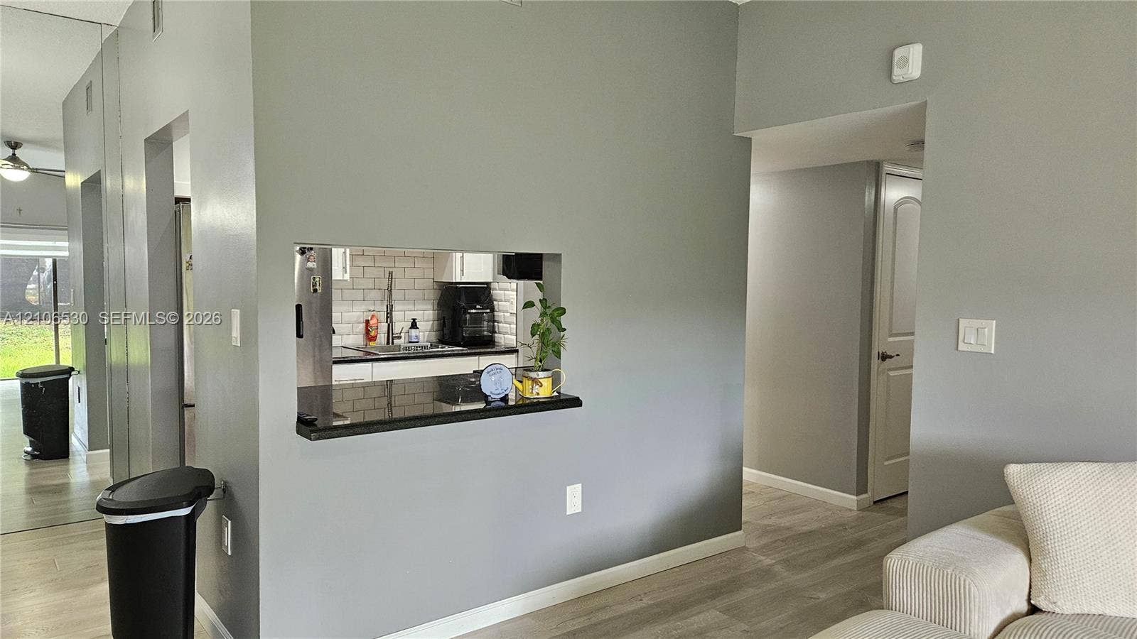 Pass-through opening featuring a dark stone countertop, neutral wall coloring, and light-toned wood-finish flooring