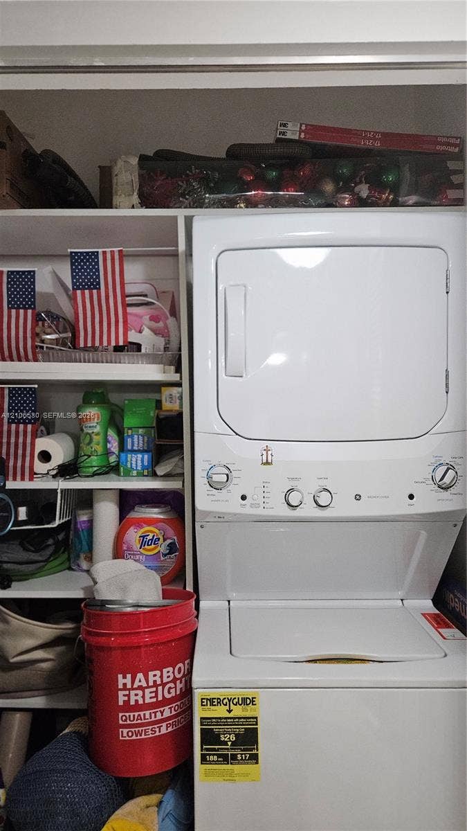 White stacked laundry unit featuring integrated shelving with tiered storage compartments