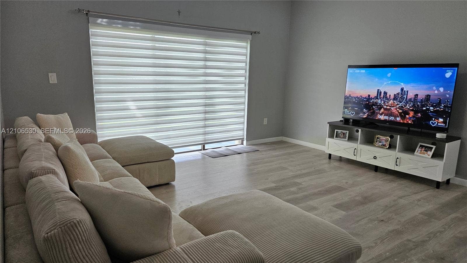 Wood-finish flooring, neutral wall tones, and sliding glass doors featuring horizontal banded roller shades