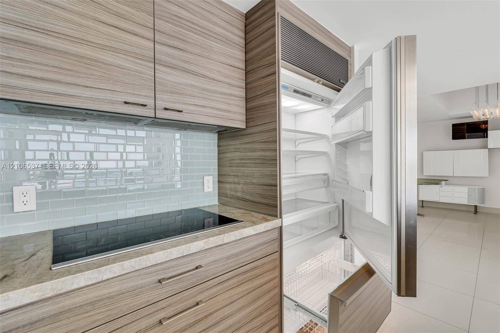 465 Brickell Avenue, #5203, Miami, FL 33131 Custom wood-finish cabinetry, built-in integrated refrigerator, stone countertop, induction cooktop, and glass tile backsplash