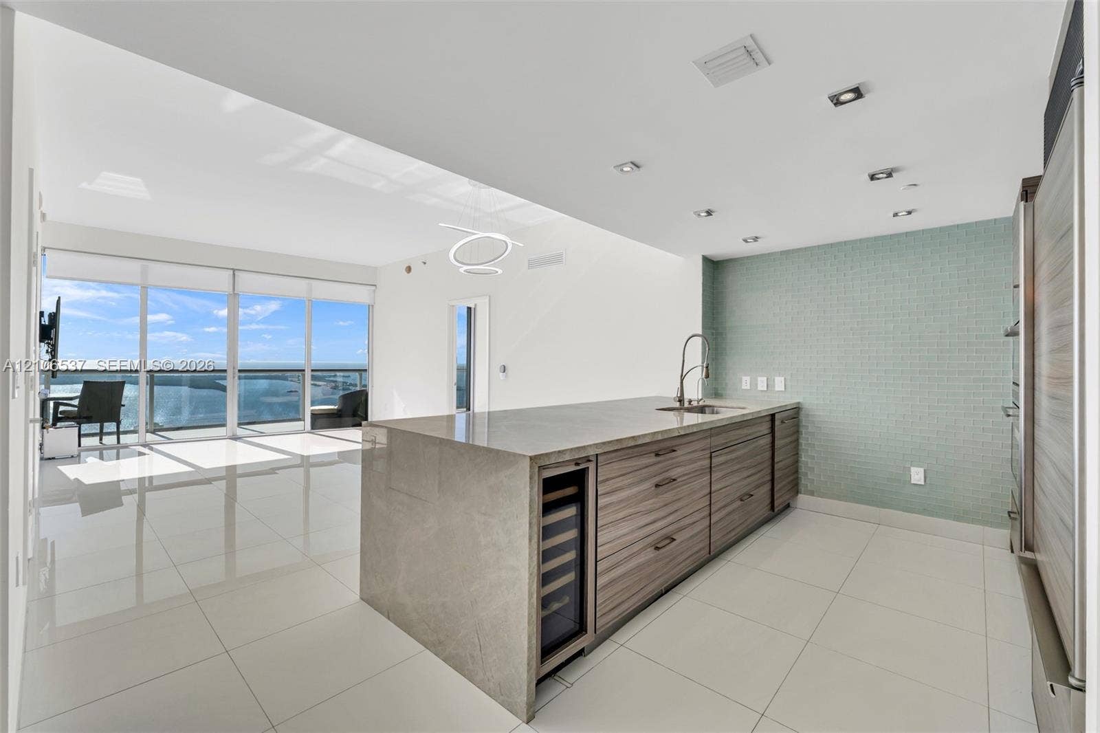 465 Brickell Avenue, #5203, Miami, FL 33131 Kitchen island featuring stone countertop, wood-finish cabinetry, built-in wine refrigerator, glass tile backsplash, and floor-to-ceiling windows