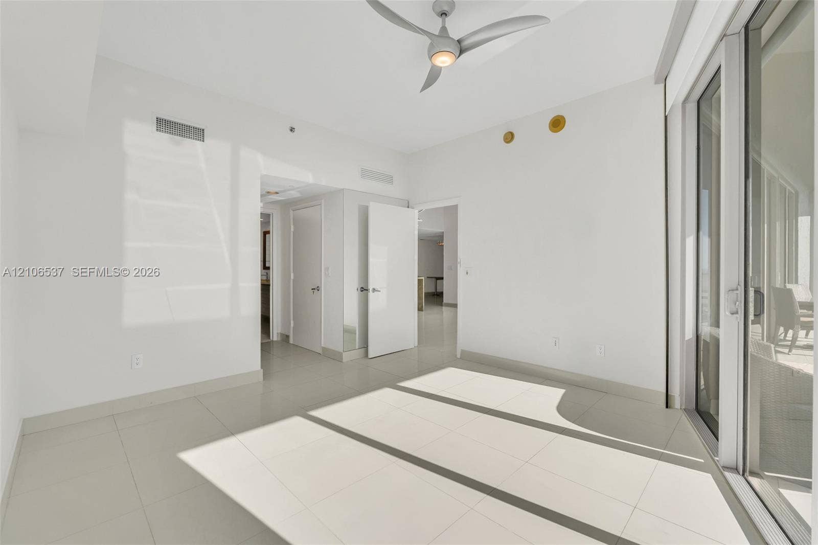 465 Brickell Avenue, #5203, Miami, FL 33131 Neutral-toned interior featuring large-format tile flooring, a modern multi-blade ceiling fan, and expansive floor-to-ceiling glass sliding doors