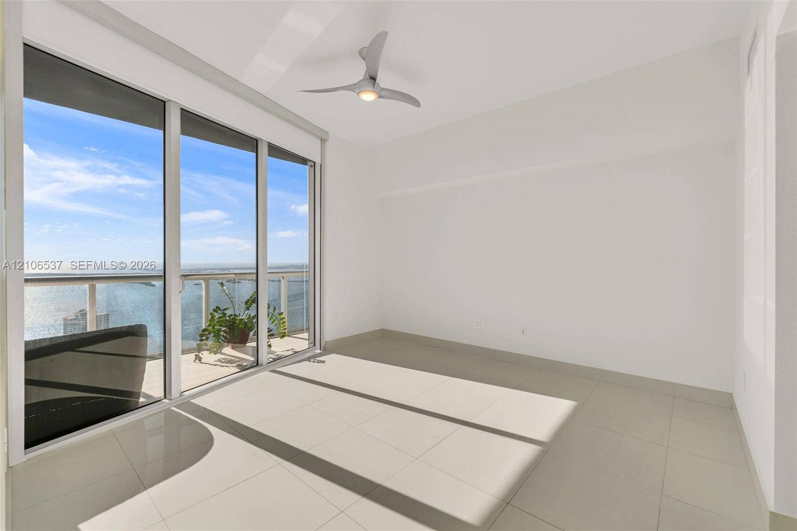 465 Brickell Avenue, #5203, Miami, FL 33131 Floor-to-ceiling sliding glass doors, balcony with glass railing, large-format tile flooring, and contemporary three-blade ceiling fan