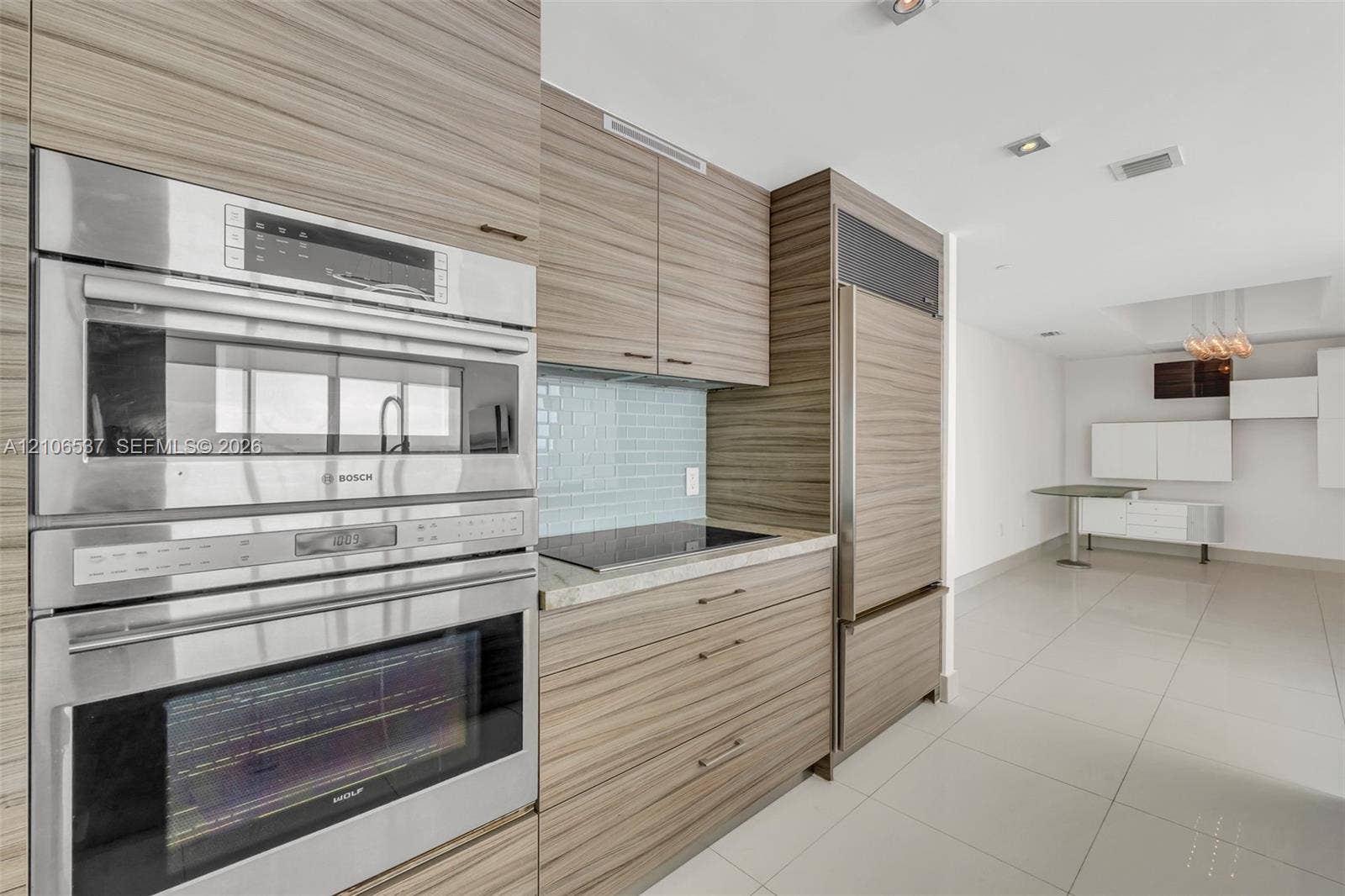 465 Brickell Avenue, #5203, Miami, FL 33131 Kitchen featuring custom wood-grain cabinetry, integrated stainless steel refrigerator, Bosch wall oven and microwave, stone countertops, and tile backsplash