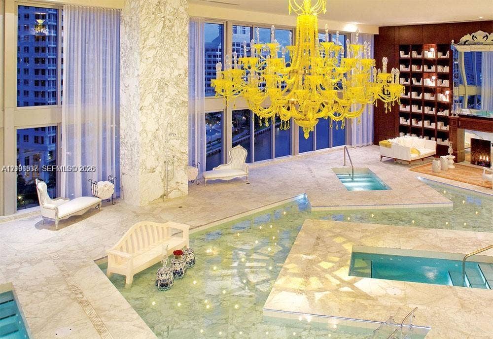 465 Brickell Avenue, #5203, Miami, FL 33131 Floor-to-ceiling windows, stone flooring, integrated aquatic features, built-in shelving, and a prominent decorative chandelier
