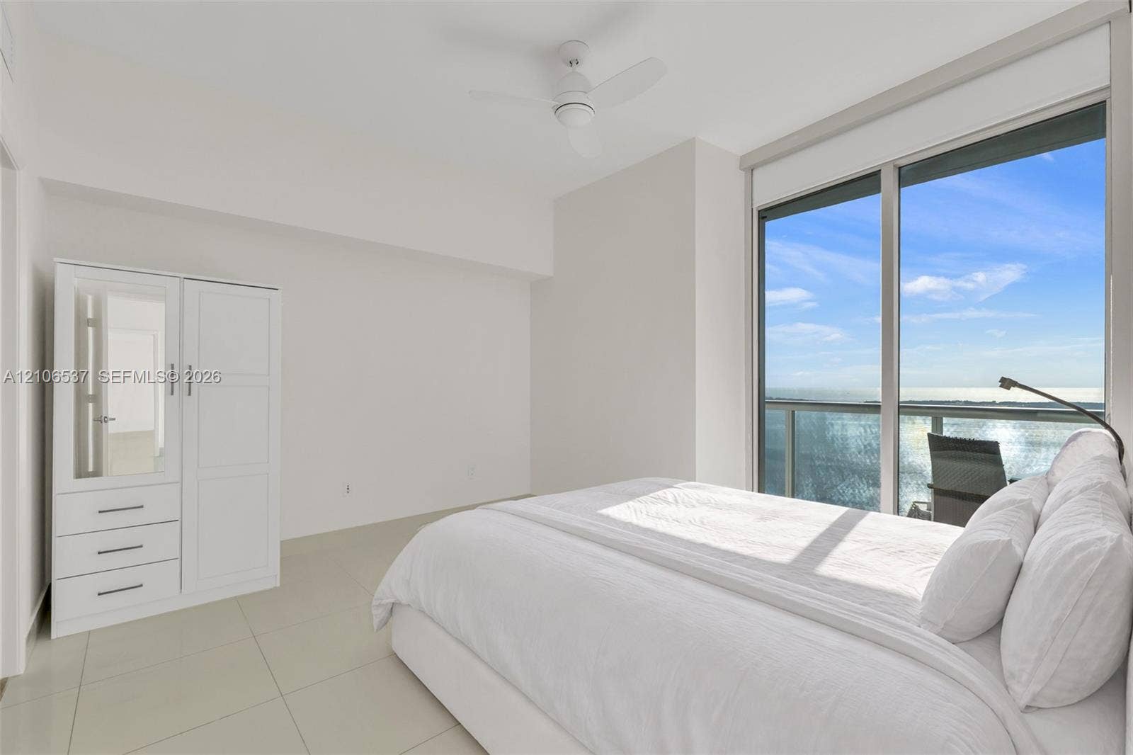 465 Brickell Avenue, #5203, Miami, FL 33131 Floor-to-ceiling sliding glass doors, neutral tile flooring, built-in white cabinetry, and a ceiling-mounted fan