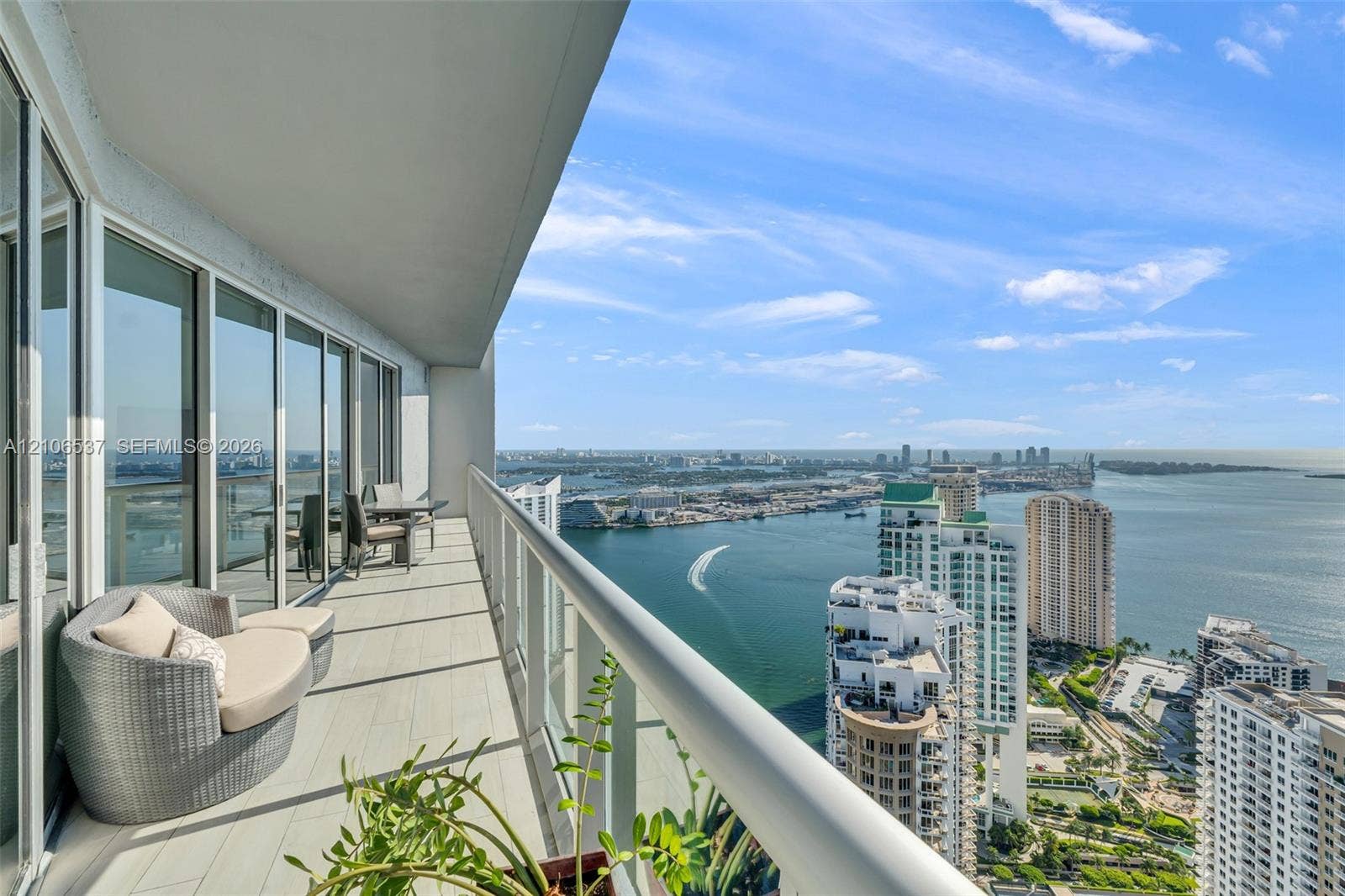 465 Brickell Avenue, #5203, Miami, FL 33131 Covered terrace with porcelain tile flooring, full-height sliding glass doors, and a glass-paneled railing overlooking the waterway and cityscape