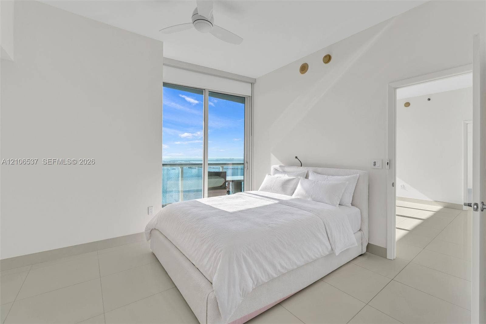 465 Brickell Avenue, #5203, Miami, FL 33131 Large-format tile flooring, ceiling fan with integrated lighting, and floor-to-ceiling glass sliding doors leading to a private balcony with water scenery