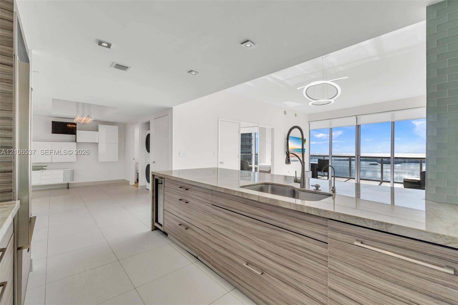 465 Brickell Avenue, #5203, Miami, FL 33131 Kitchen featuring flat-panel wood-finish cabinetry, stone countertops, stainless steel undermount sink with a pull-down faucet, large-format tile flooring, and floor-to-ceiling windows