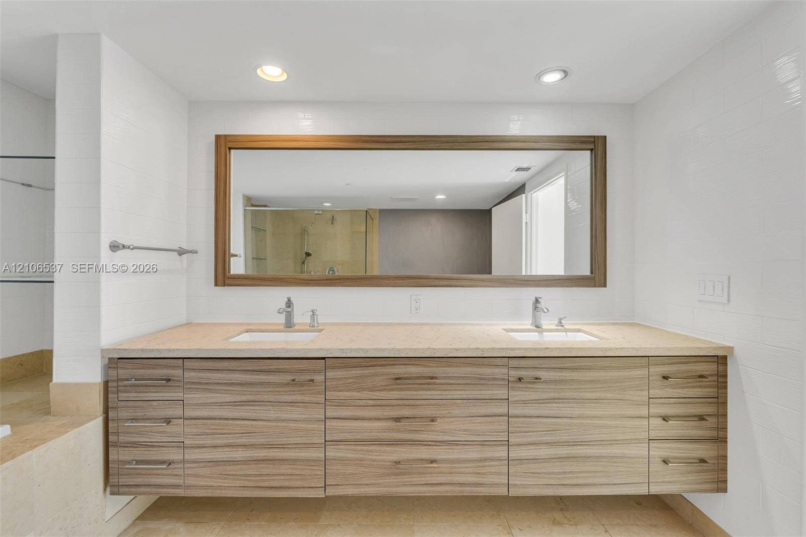 465 Brickell Avenue, #5203, Miami, FL 33131 Floating vanity featuring wood-grain cabinetry, dual undermount sinks, stone-surface countertop, and a large framed mirror with integrated recessed lighting