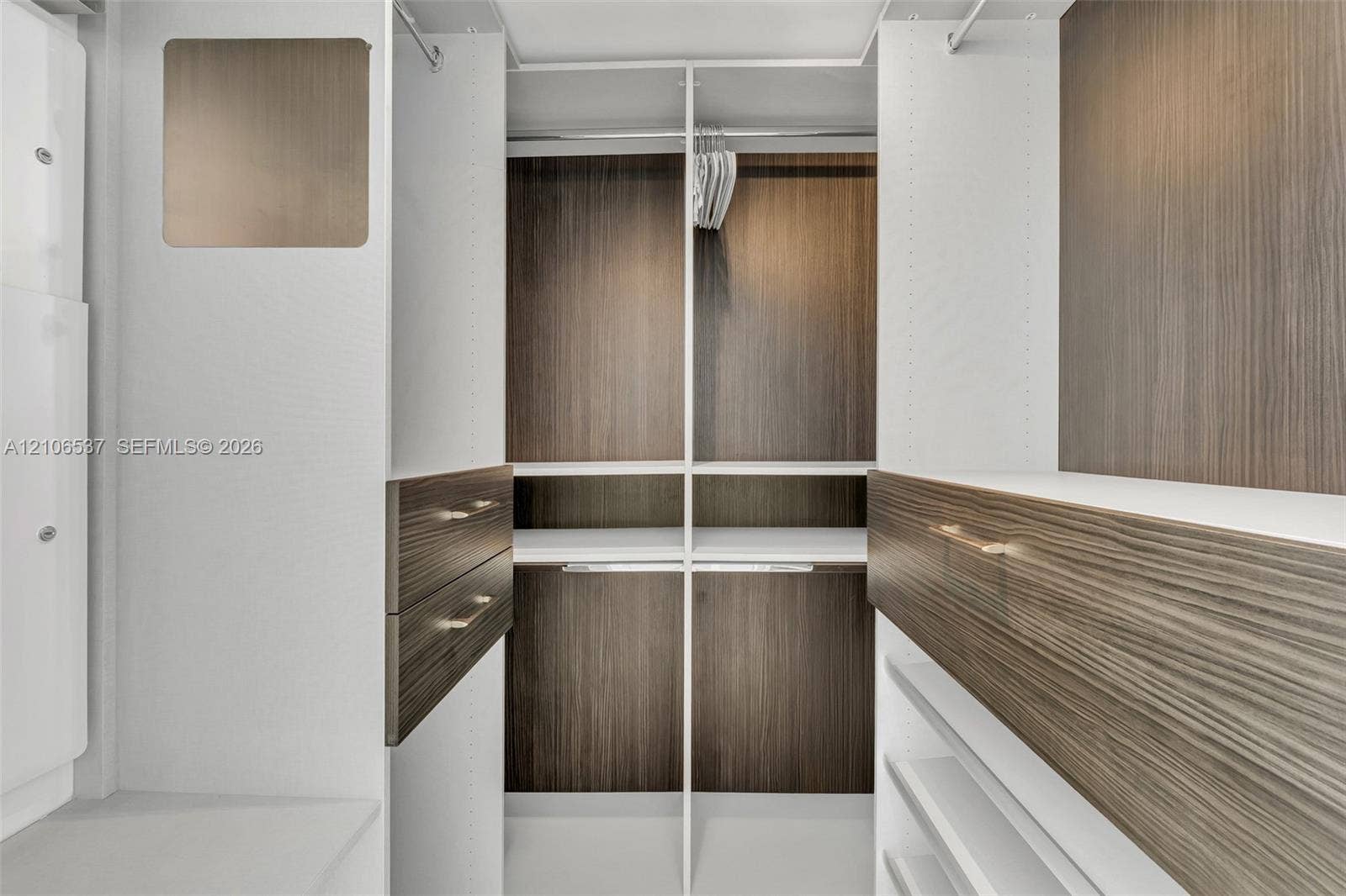 465 Brickell Avenue, #5203, Miami, FL 33131 Custom closet system featuring wood-finish cabinetry, built-in shelving, integrated hanging rods, and drawers with metallic hardware