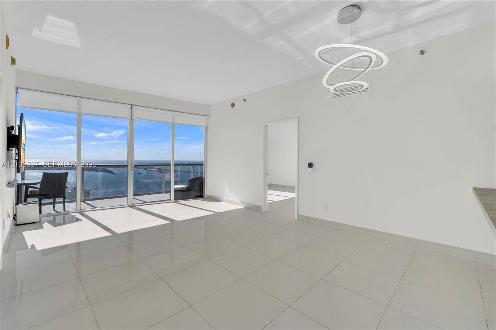 465 Brickell Avenue, #5203, Miami, FL 33131 Living area featuring large-format tile flooring, floor-to-ceiling glass sliding doors, a metal-railing balcony, and a contemporary multi-ring LED chandelier