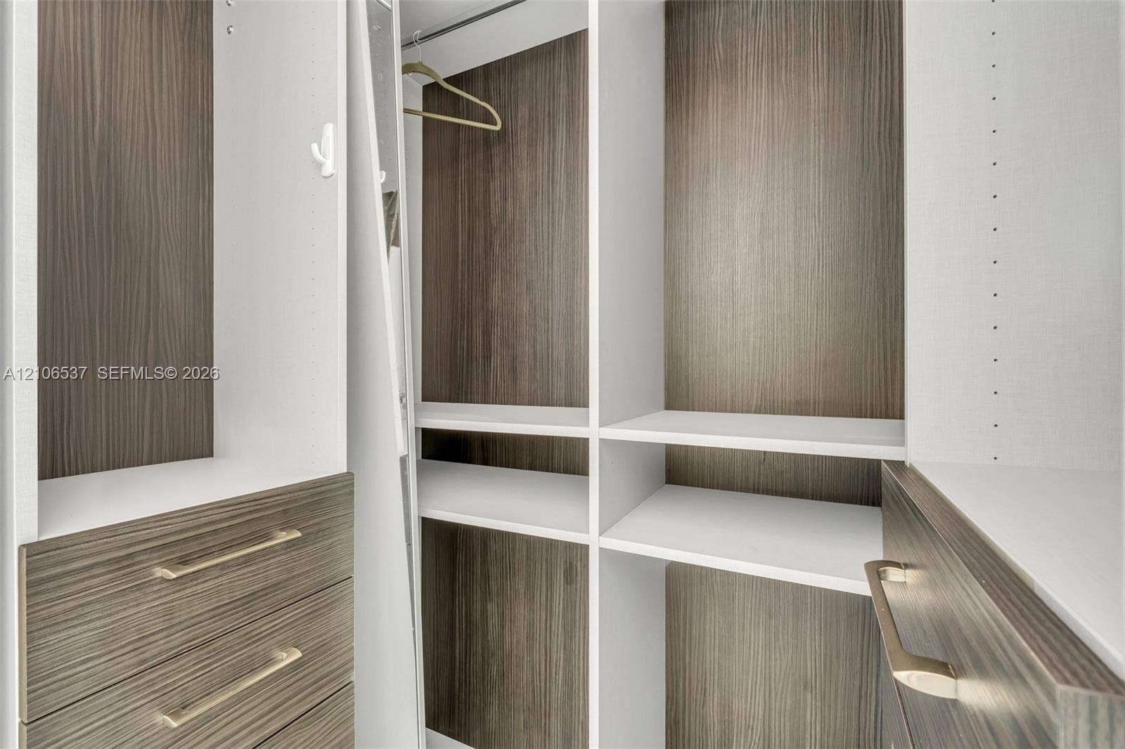 465 Brickell Avenue, #5203, Miami, FL 33131 Custom closet organization system featuring wood-finish cabinetry, adjustable shelving, integrated drawer storage, and satin-finish metal hardware