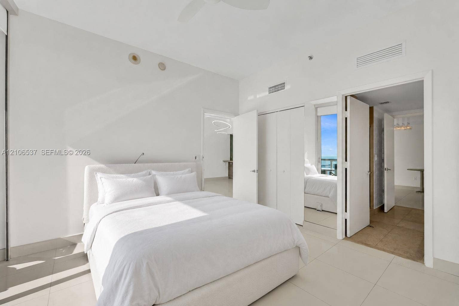 465 Brickell Avenue, #5203, Miami, FL 33131 Bright room featuring large-format tile flooring, high ceilings with recessed lighting, double-door closet storage, and a private balcony with water scenery