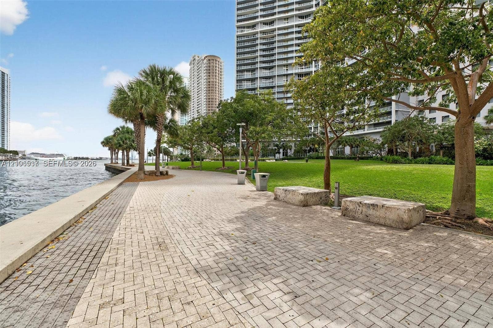 465 Brickell Avenue, #5203, Miami, FL 33131 Waterfront paved walkway featuring stone seating, mature trees, manicured lawn areas, and concrete curbing