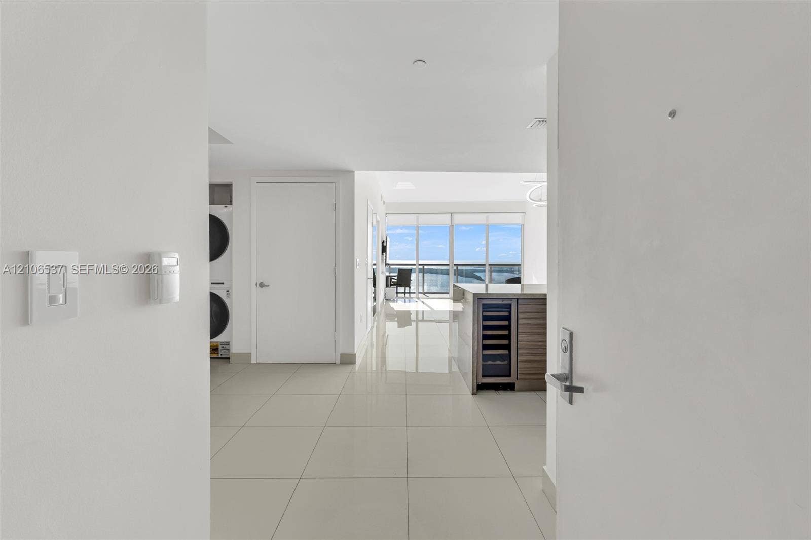 465 Brickell Avenue, #5203, Miami, FL 33131 Large-format tile flooring, built-in wine refrigerator, wood-finish kitchen cabinetry, stacked laundry unit, and floor-to-ceiling windows