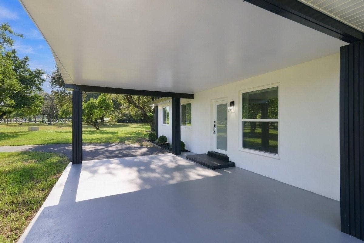 Vaulted ceiling with exposed wood beams, light-toned stone-finish flooring, and multiple windows