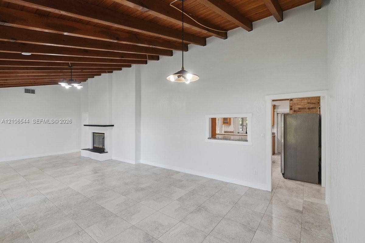 Vaulted wood-plank ceiling featuring recessed lighting, tile flooring, built-in cabinetry, center island with stone surfacing, and stone-accented fireplace surround