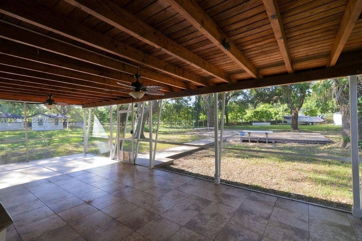 Expansive lot featuring a wood-plank walkway, raised timber platform, integrated benches, mature canopy trees, and stone ground cover