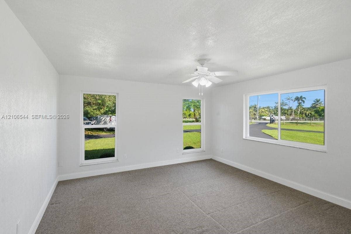 Neutral interior featuring wall-to-wall carpeting, a white ceiling fan with integrated lighting, and multiple doorways