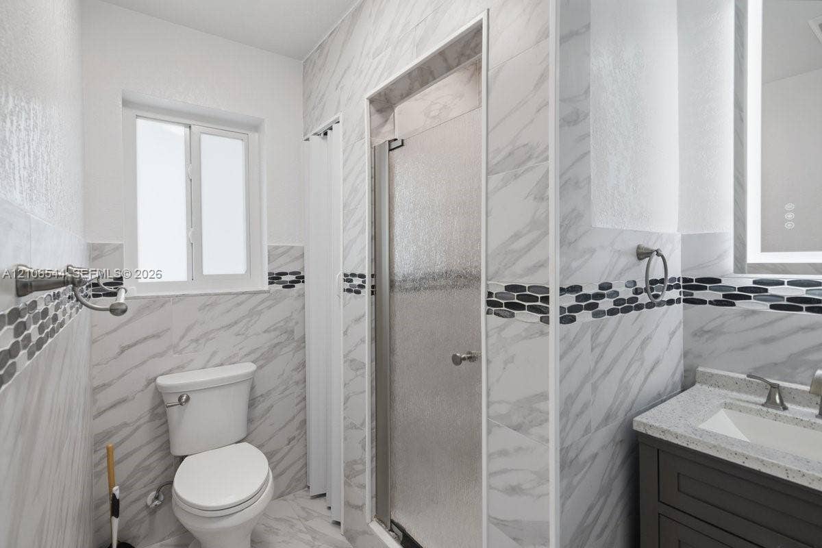 Hallway featuring neutral-toned tile flooring, recessed ceiling lighting, crisp white walls, and matte black door hardware