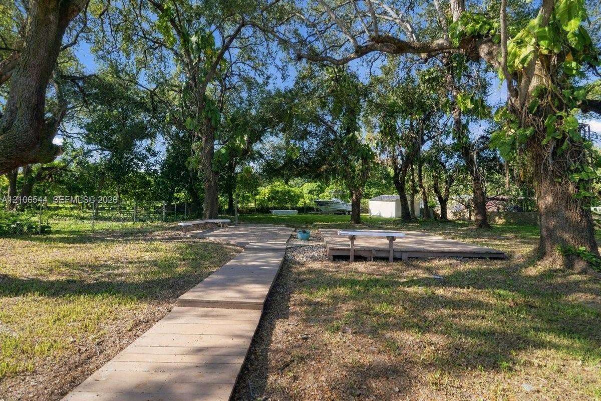 Rear grounds featuring an elevated composite deck, stone-accented hardscaping, and mature canopy trees