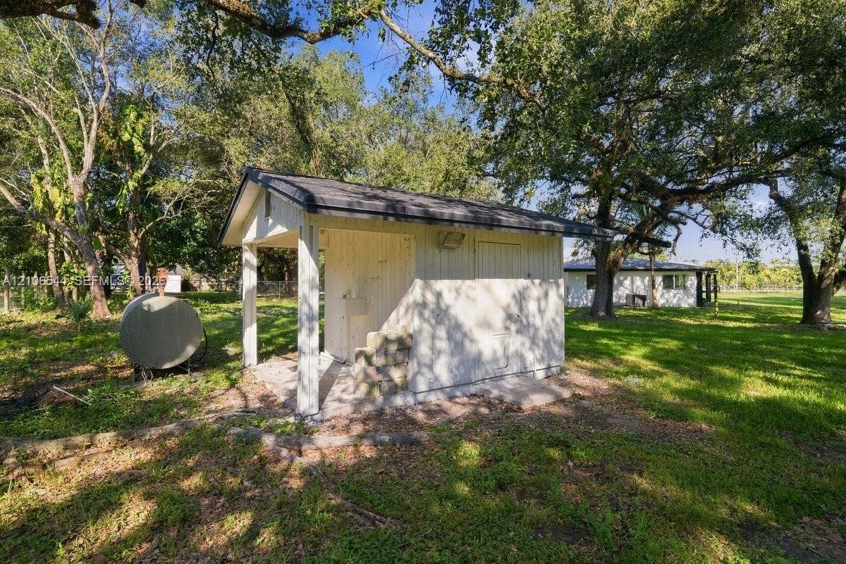 Expansive grounds featuring mature shade trees, a manicured lawn, and post-and-wire perimeter fencing