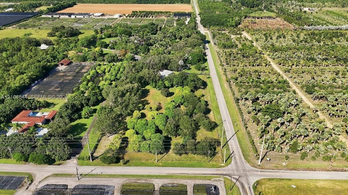 Extensive acreage featuring mature tree canopy, cleared grass areas, and paved road frontage