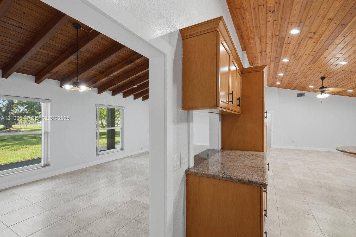Interior space featuring neutral-toned carpeting, three sliding windows, and a white ceiling fan with integrated lighting
