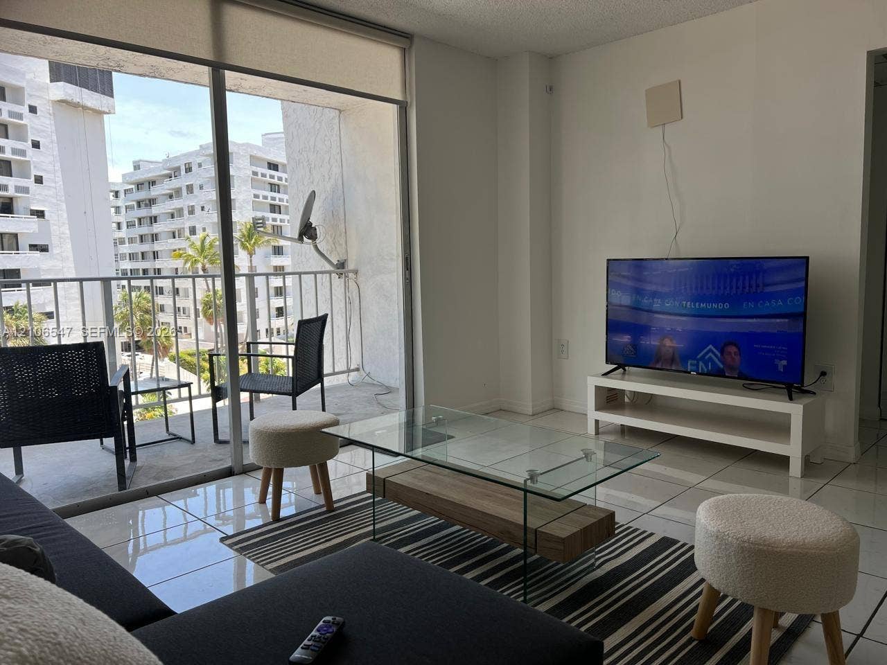 6801 Indian Creek Drive, #509, Miami Beach, FL 33141 Floor-to-ceiling sliding glass doors, white tiled flooring, and a private balcony with metal railing