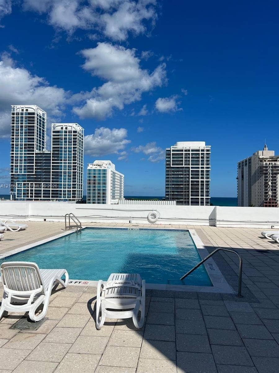 6801 Indian Creek Drive, #509, Miami Beach, FL 33141 Rooftop pool with tile surround, metal handrails, and surrounding urban skyline