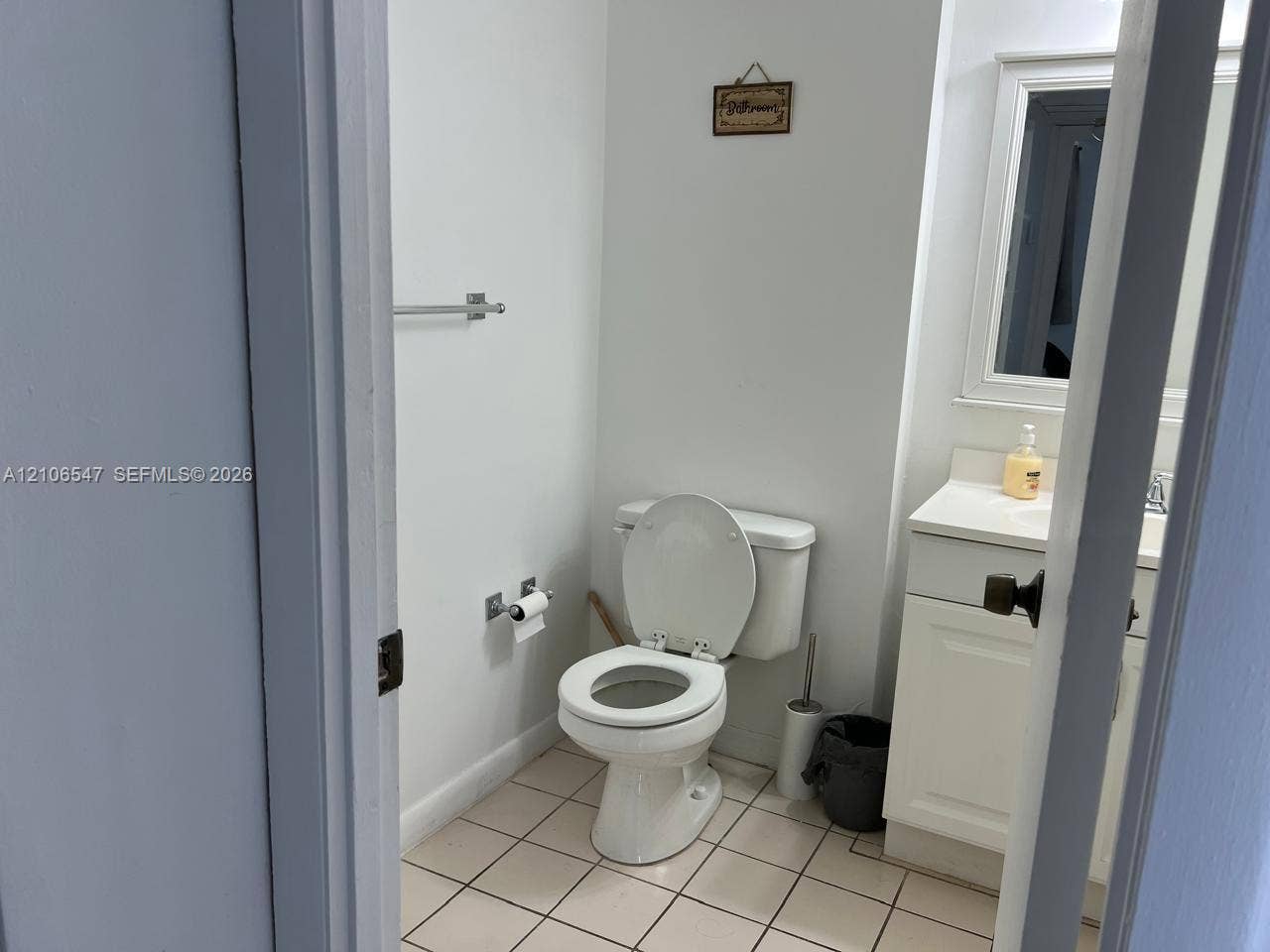 6801 Indian Creek Drive, #509, Miami Beach, FL 33141 Bathroom featuring a white vanity cabinet with a integrated countertop, framed wall mirror, tiled flooring, and polished chrome hardware