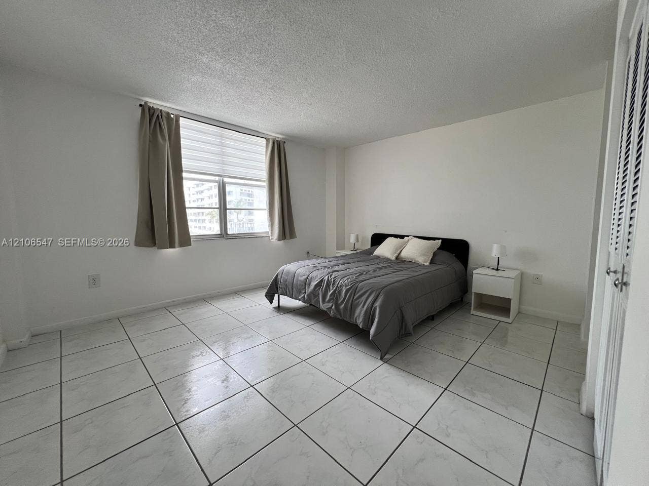 6801 Indian Creek Drive, #509, Miami Beach, FL 33141 Large-format neutral tile flooring, multi-pane window, and louvered closet doors