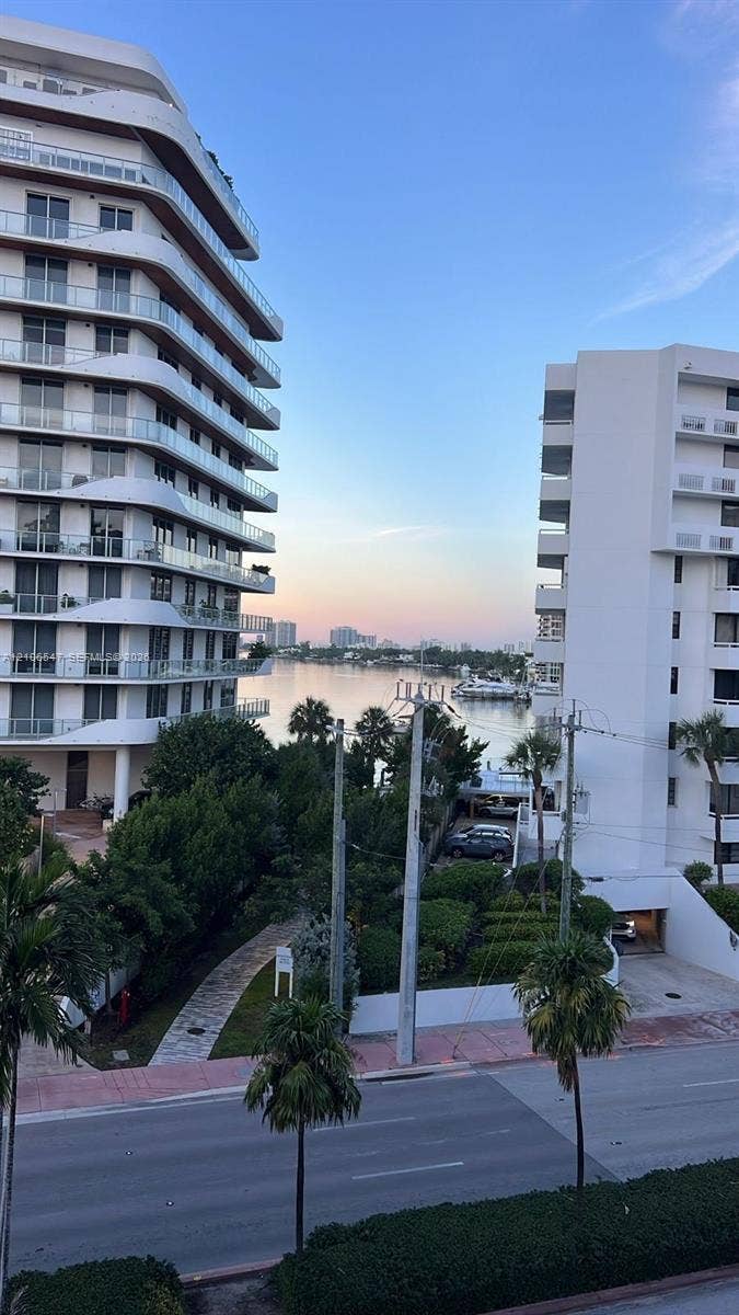 6801 Indian Creek Drive, #509, Miami Beach, FL 33141 High-rise residential exterior with glass panel balconies, surrounded by mature palm trees and coastal waterway