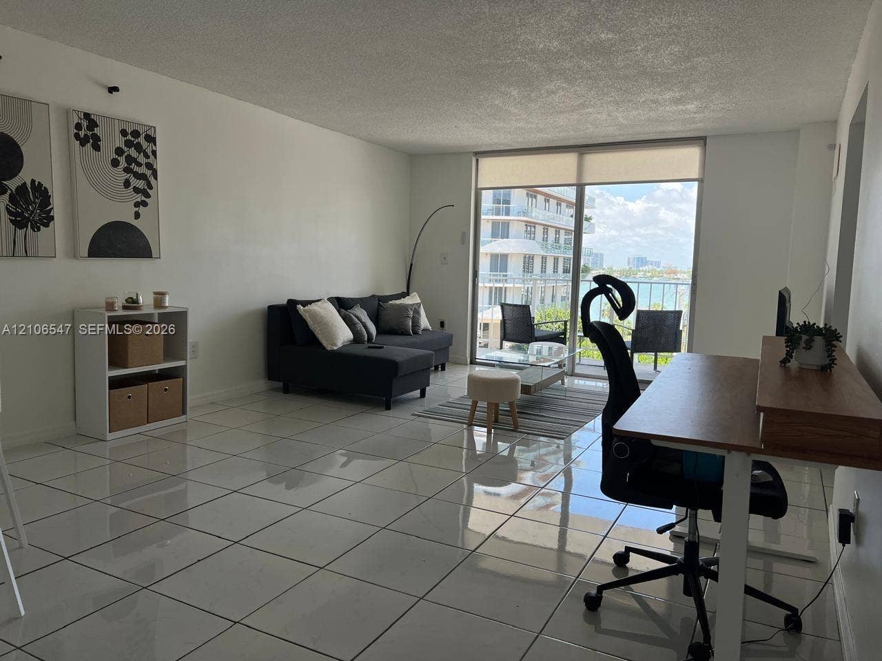 6801 Indian Creek Drive, #509, Miami Beach, FL 33141 Living area featuring large-format ceramic tile flooring, neutral wall finishes, and floor-to-ceiling glass sliding doors opening to a private balcony