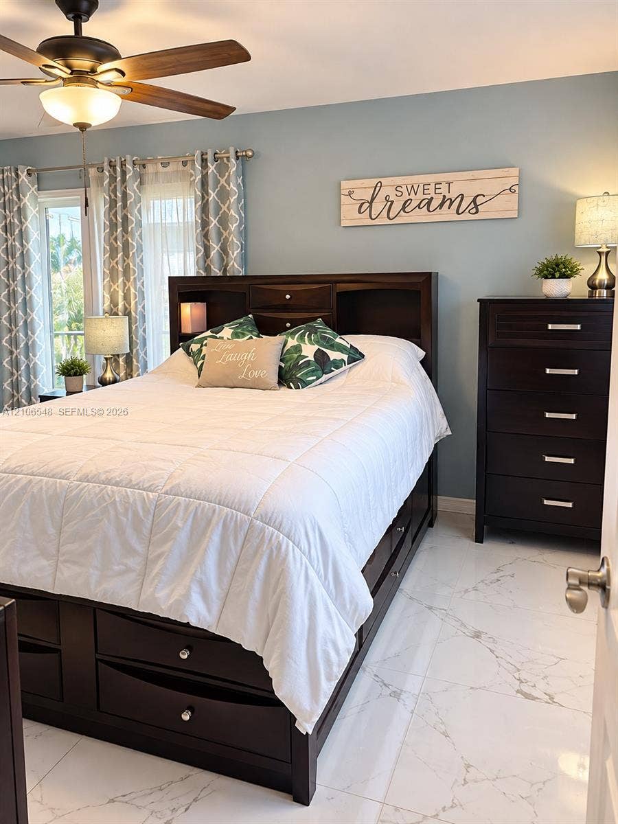 Polished stone-finish flooring with veining, multi-speed ceiling fan with integrated light fixture, and glass sliding door featuring metallic hardware