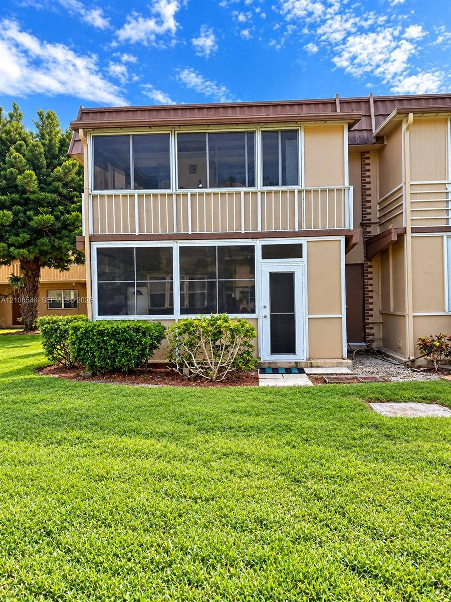 Two-story exterior featuring a screened balcony and lower-level screened porch, stucco siding, and a metal roof