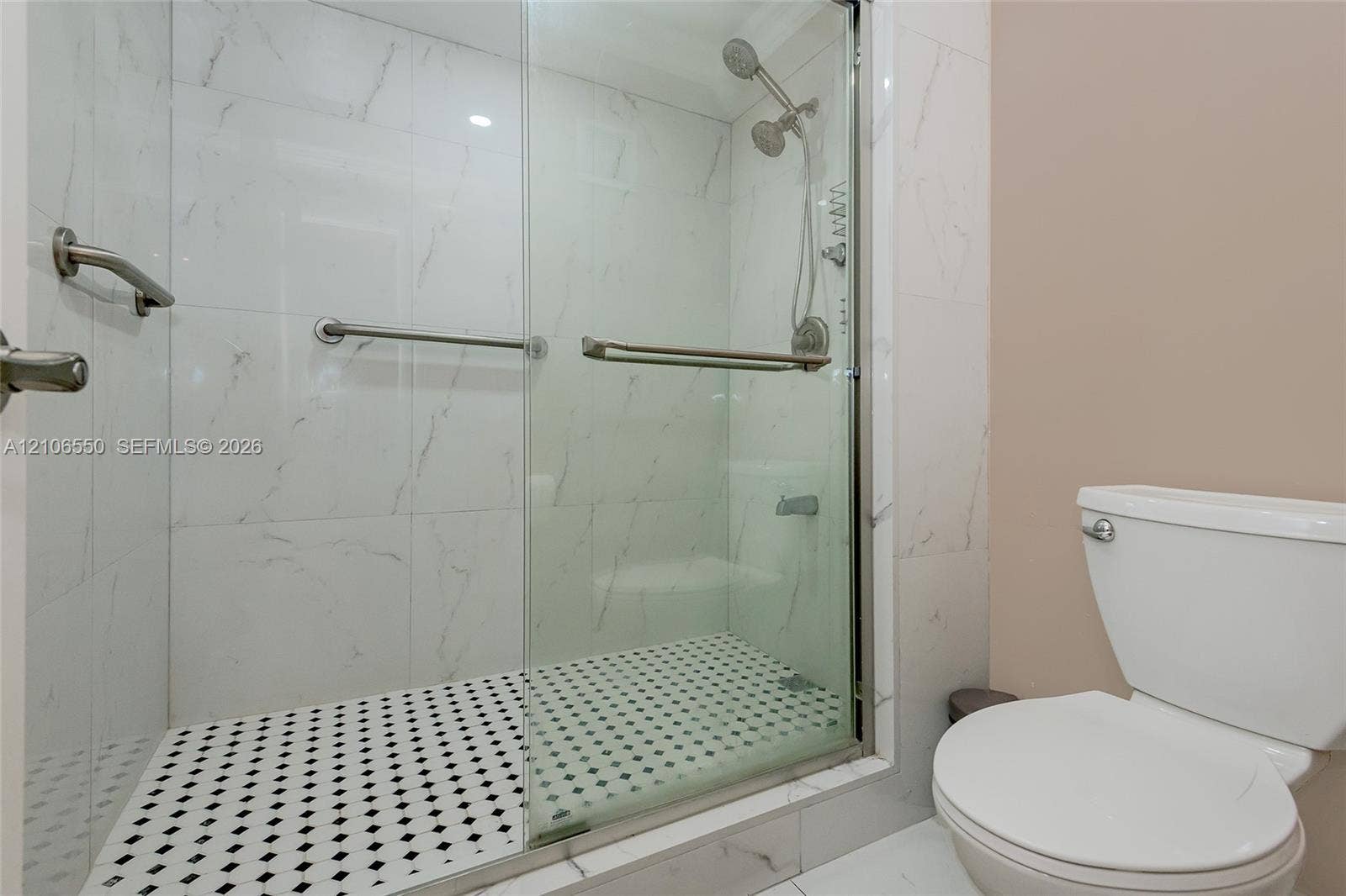 Walk-in shower featuring large-format stone-look wall tiling, a mosaic tile floor, glass sliding doors, and chrome fixtures