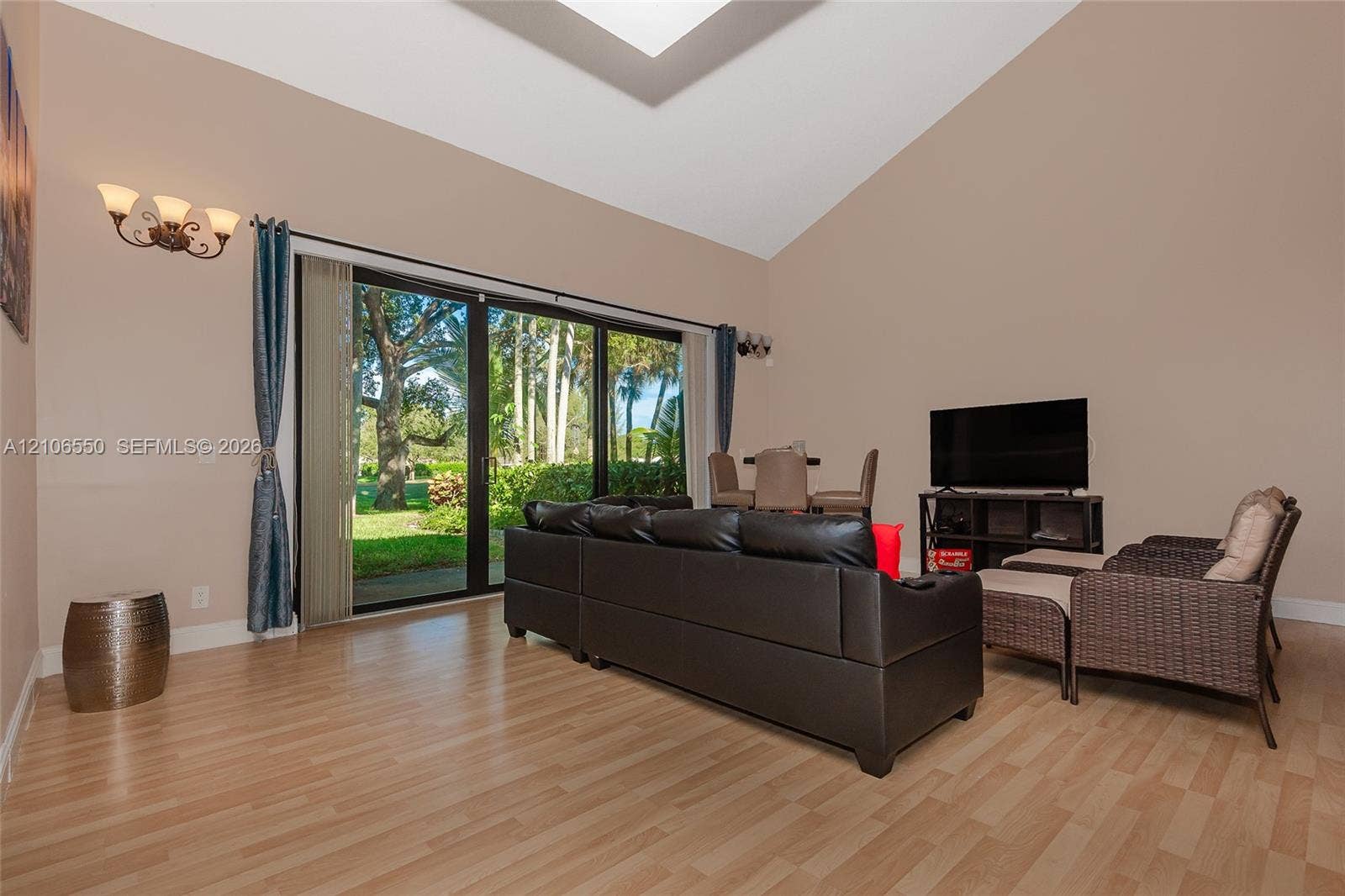 Vaulted ceiling with skylight, wood-finish flooring, and expansive sliding glass doors