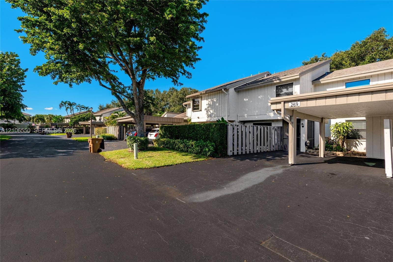Multi-level exterior featuring vertical siding, an attached covered carport, and private fenced patio area