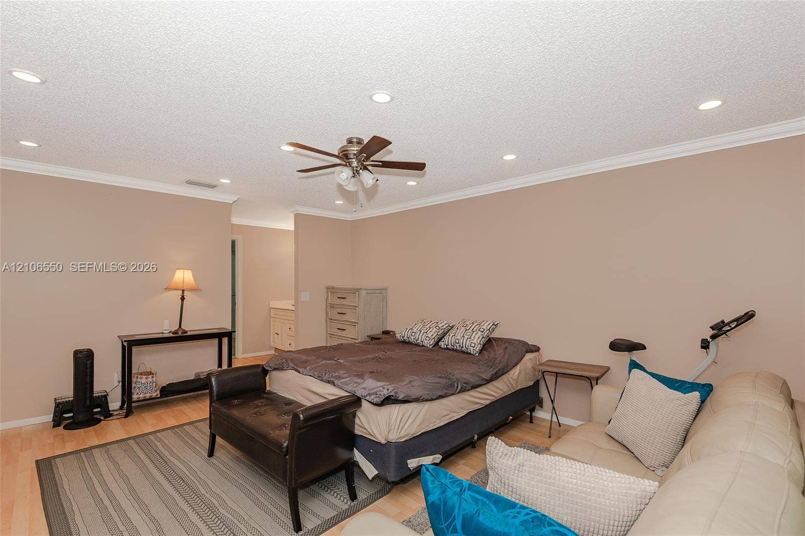 Spacious room featuring light-toned wood-finish flooring, recessed lighting, crown molding, and a central ceiling fan