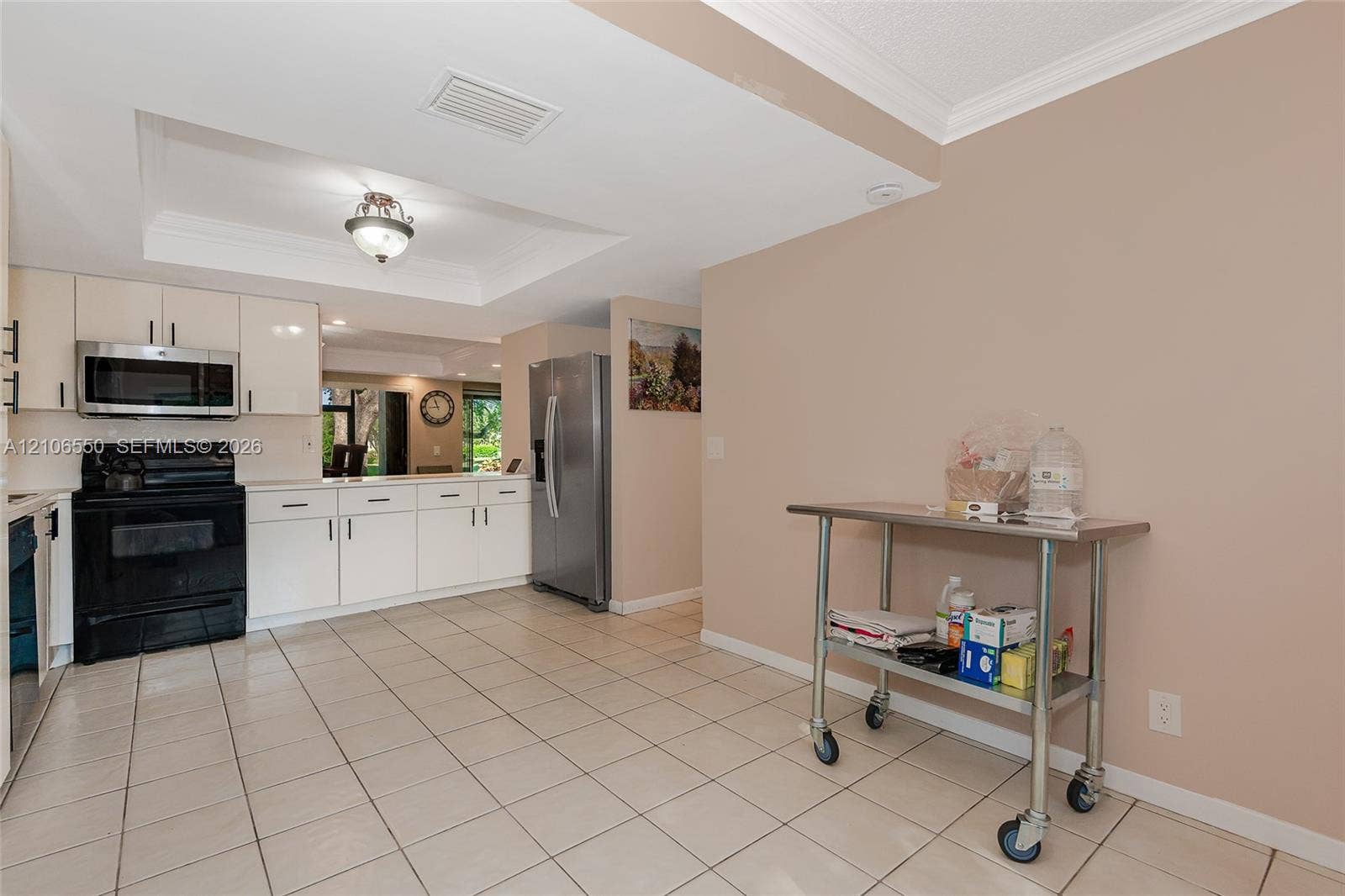 Kitchen featuring white flat-panel cabinetry, stainless steel appliances, tiled flooring, and a tray ceiling with recessed lighting