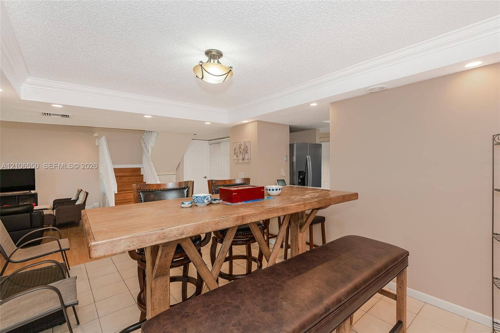 Open-concept space featuring ceramic tile flooring, recessed lighting, crown molding, and a built-in stairwell with wood-finish steps