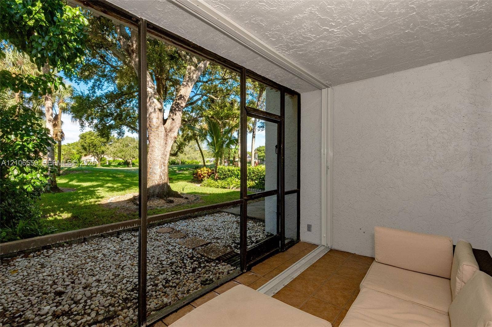 Screened-in patio featuring textured walls, tile flooring, and metal-framed screen enclosures