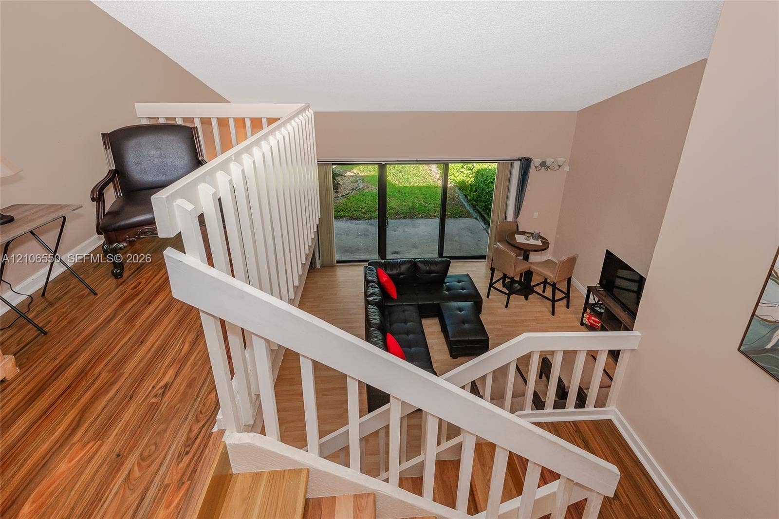 Elevated loft featuring a white wooden staircase railing and wood-finish flooring