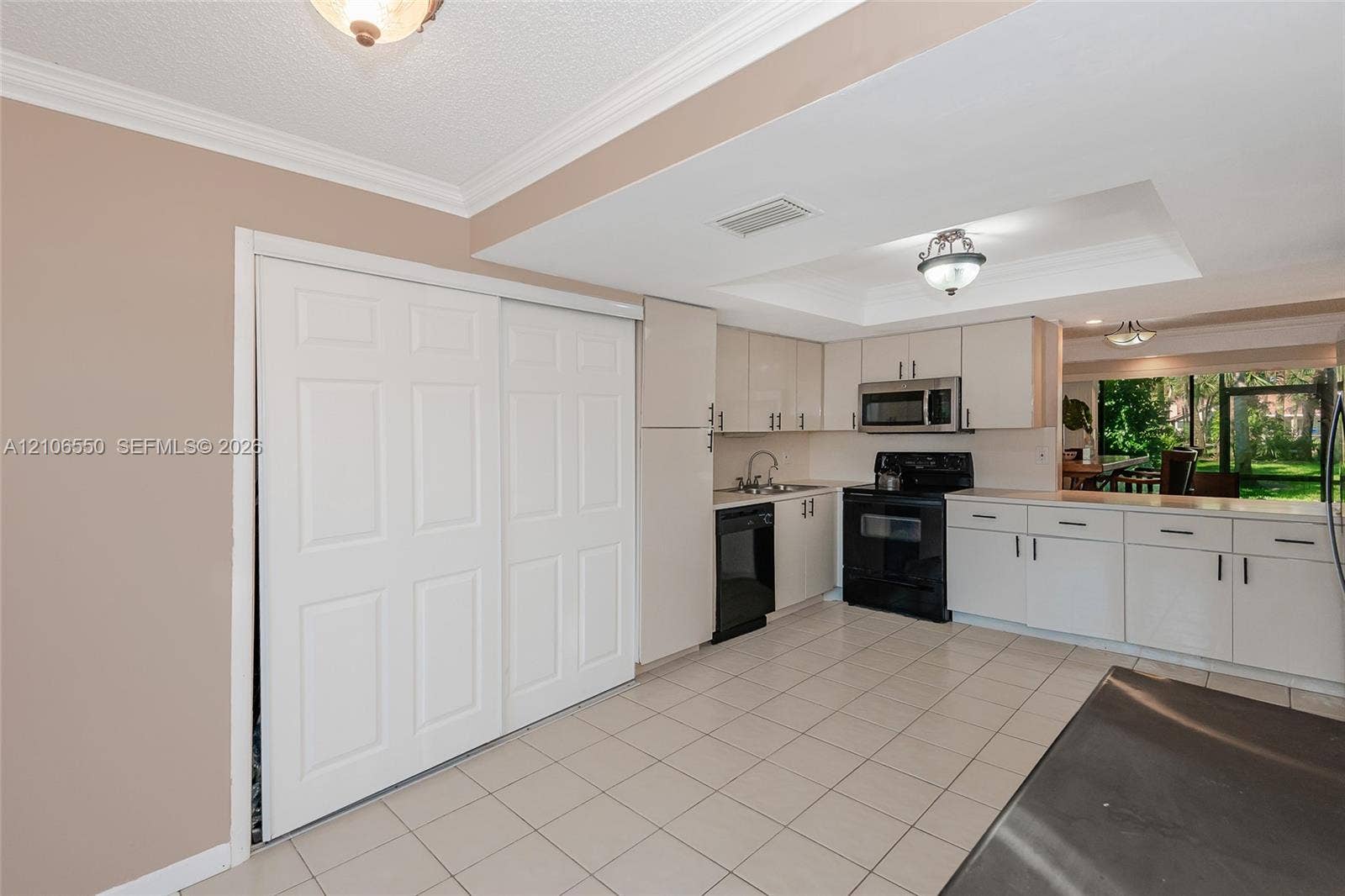 Kitchen featuring cabinetry with flat-panel doors, ceramic tile flooring, recessed ceiling lighting, and a suite of black appliances