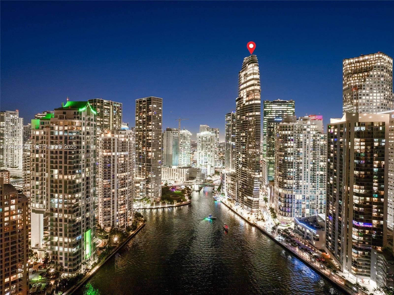 300 Biscayne Boulevard Way, #3002E, Miami, FL 33131 High-rise residential tower featuring a prominent cylindrical architectural design, floor-to-ceiling glass paneling, and proximity to a central waterway