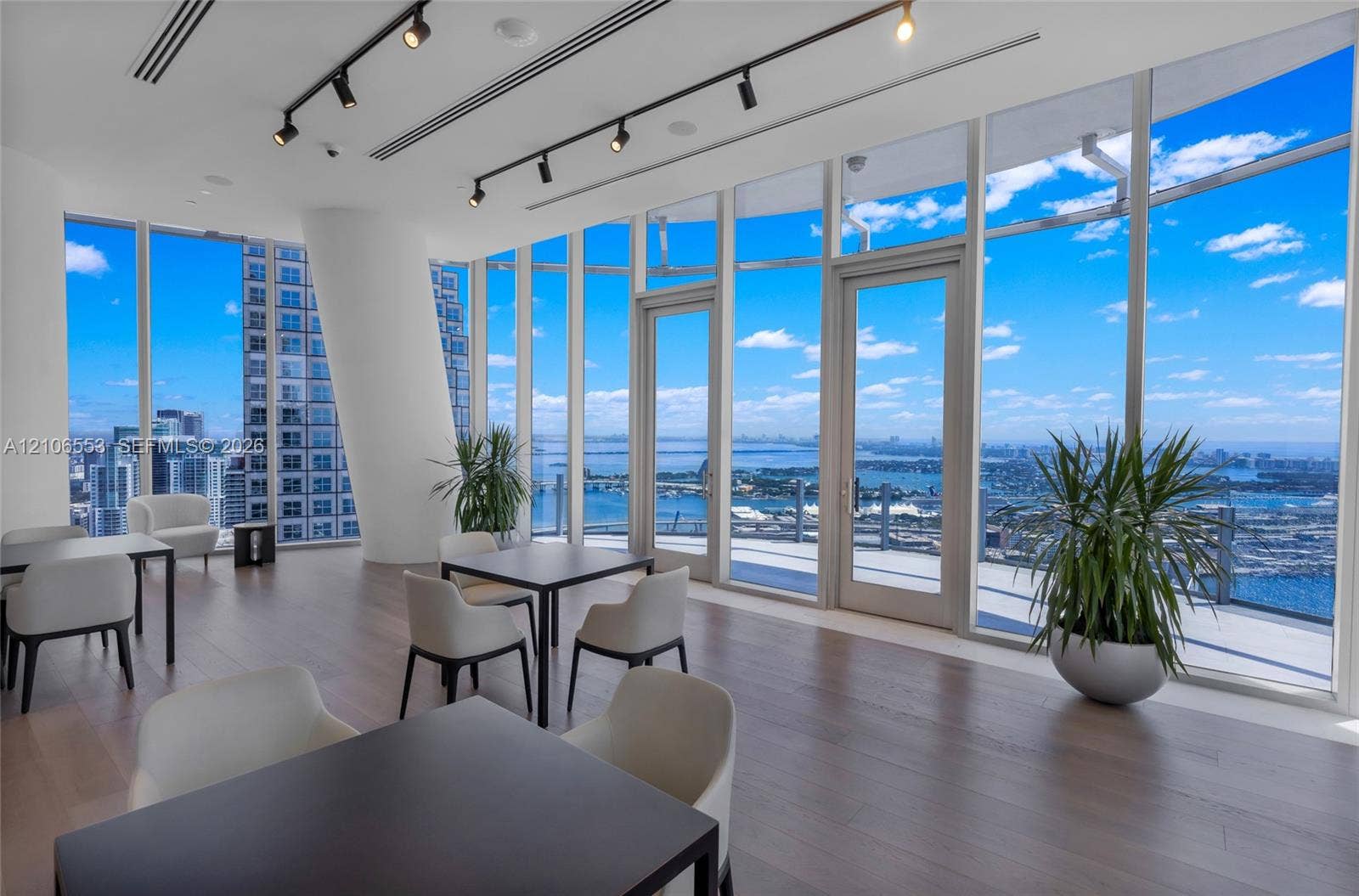 300 Biscayne Boulevard Way, #3002E, Miami, FL 33131 Floor-to-ceiling glass windows, wide-plank wood-finish flooring, linear track lighting, and double glass-paneled doors opening to an exterior terrace